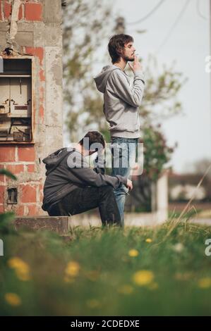 Zwei Freunde sitzen auf Treppen und Rauchen von Cannabis oder Haschisch gemeinsame in verlassenen Ghetto Teil der Stadt Stockfoto