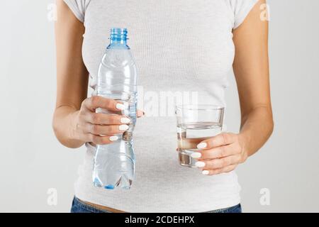 Athletische Frau, die eine Flasche und ein Glas Wasser in den Händen hält. Gesundes Lifestyle-Konzept. Stockfoto