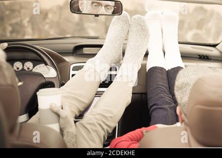 Entspannen Sie sich Zeit nach einer langen Reise. Ohne Schuhe und mit einem heißen Getränk. Ältere Paare fühlen sich wie Teenager. Reise- und Relax-Konzept – Bild Stockfoto