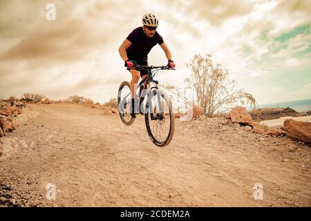 Radfahrer im violetten T-Shirt mit dem Mountainbike. Mann auf dem Mountainbike fährt an einem stürmischen Tag auf dem Trail. Extreme Sport Concept - Bild Stockfoto