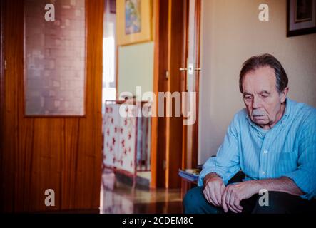 Trauriger alter Mann im Schlafanzug, der in einem isolierten Sessel sitzt - älterer trauriger Mann aus der Nähe - Portrait - Fokus Auf Flächen Stockfoto