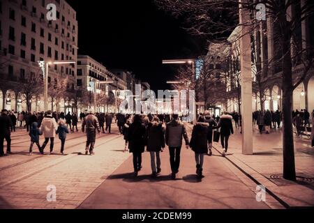 Asphaltstraße, die nachts in die Stadt führt. Menschenmenge in einer Einkaufsstraße. Modernes Wettbewerbslebenskonzept. Nicht erkennbare Masse von Menschen gehen. Stockfoto
