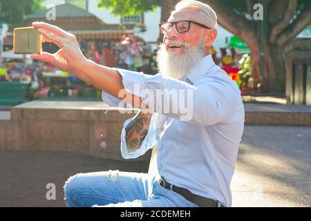 Senior Hipster Mann mit Smartphone für ein Selfie. Glücklicher Mann bei einer Videokonferenz mit ihrer Freundin. Tech und fröhliche ältere Lifestyle-Konzept - FOC Stockfoto