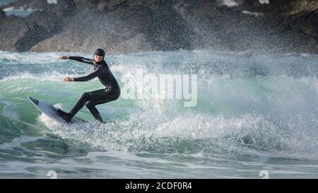 Ein Panoramabild eines jungen Surfers, der eine Welle bei Fistral in Newquay in Cornwall reitet. Stockfoto