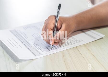 Abstimmungskonzept. Die Hand eines asiatischen Mannes gibt bei den US-Wahlen die Stimme auf dem Stimmzettel ab. Stockfoto