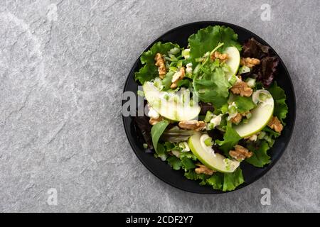 Frischer Waldorfsalat mit Salat, grünen Äpfeln, Walnüssen und Sellerie auf grauem Stein Stockfoto