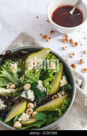 Salat mit Birnen, gerösteten Haselnüssen, Blauschimmelkäse und Brombeersoße. Stockfoto