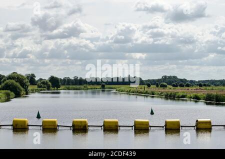 Gelbe Stahlseilmaschinen als Barriere im Fluss Vecht bei Zwolle, Niederlande, um Boote von der Staumauer fernzuhalten Stockfoto