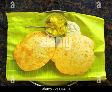 Traditionelle indische Küche - zwei gebratene Kuchen (puri) mit Gemüsecurry und Kokosnuss-Chatni auf Bananenblatt im Restaurant von Madurai, Tamil Nadu, Indien Stockfoto