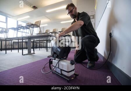 Eine Nebelmaschine, die ein ganzes Klassenzimmer desinfizieren kann, wird in einem Klassenzimmer der Ark Charter Academy in Portsmouth aufgestellt, da die Vorbereitungen vor Beginn des neuen Semesters getroffen werden. Stockfoto