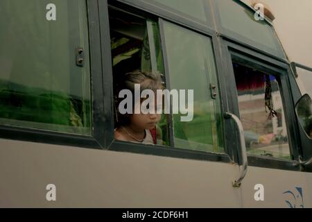 Ein Kind, das durch ein Fenster eines Busses schaut, während es auf der Straße hält, die nach Dhulikhel am Stadtrand von Kathmandu, Nepal, führt. Stockfoto