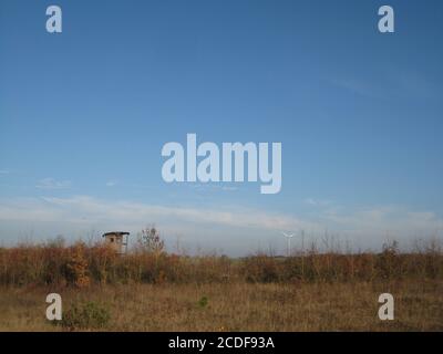 Der hölzerne hohe Sitz des Jägers auf dem leeren Feld Unter blauem Himmel Stockfoto