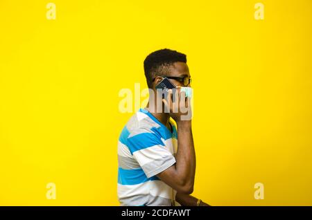 Junger schöner afrikanischer Mann trägt Gesichtsmaske isoliert über gelb Hintergrund Stockfoto