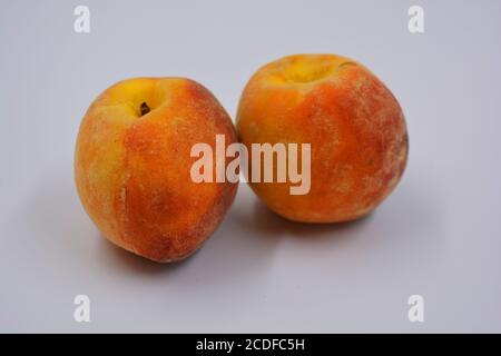 Zwei große reife rot-orange leckere Pfirsiche auf einem weißen Teller. Gesundes und wunderbares Essen für jeden Tag. Stockfoto