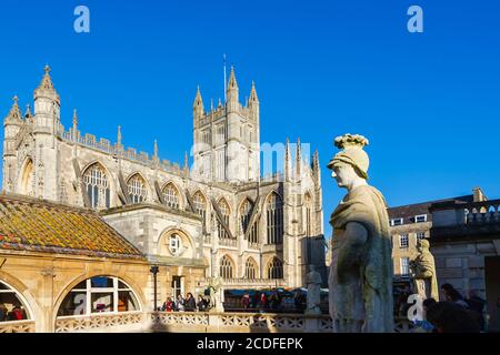 Verwitterte Kalksteinstatue auf der Terrasse der berühmten römischen Bäder in Bath, Somerset, Südwestengland mit Bath Abbey dahinter Stockfoto