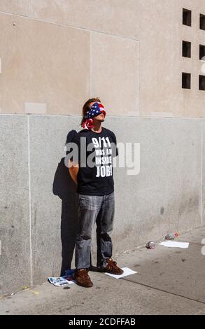 Ein junger amerikanischer Mann steht mit verbundenen Augen am World Trade Center in New York und trägt ein schwarzes T-Shirt mit der Aufschrift: "9/11 war ein Innenjob!" Stockfoto