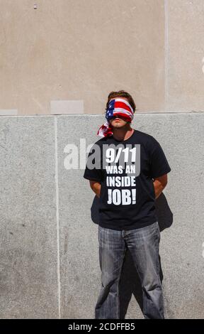 Ein junger amerikanischer Mann steht mit verbundenen Augen am World Trade Center in New York und trägt ein schwarzes T-Shirt mit der Aufschrift: "9/11 war ein Innenjob!" Stockfoto