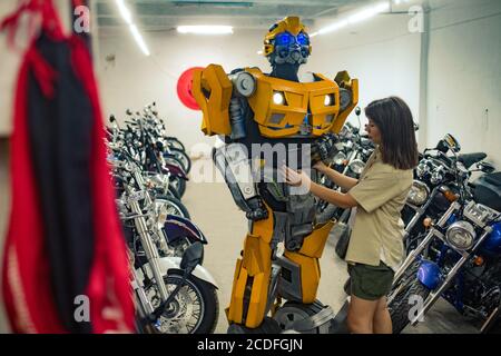 Mädchen steht in der Nähe Roboter Transformator und repariert ihn in der Garage. Stockfoto