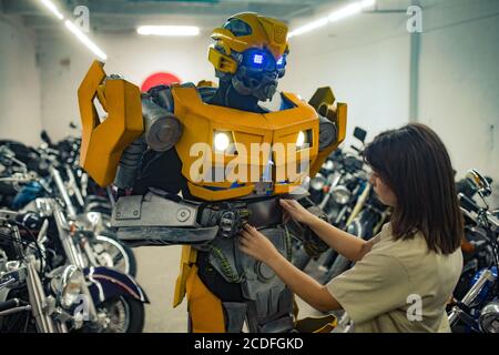 Mädchen steht in der Nähe Roboter Transformator und repariert ihn in der Garage. Stockfoto