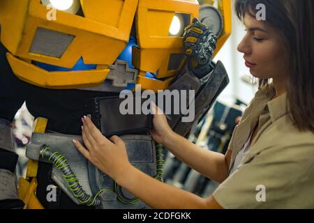 Mädchen steht in der Nähe Roboter Transformator und repariert ihn in der Garage. Stockfoto