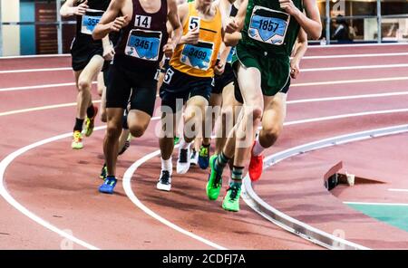 Viele Männer laufen eine Meile auf einer Indoor-Banked Track bei einem Track and Field Wettbewerb. Stockfoto