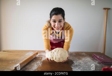 Fröhliche Frau hält Teig bereit zum Backen. Backen hausgemachtes Brot, Gebäck Stockfoto