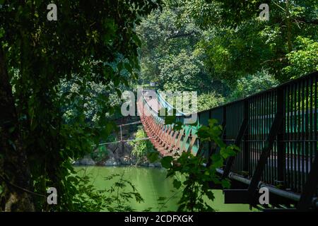 Eine hölzerne Hängebrücke über den Fluss im Wald Stockfoto