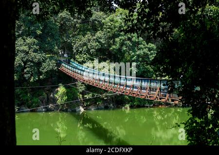 Eine hölzerne Hängebrücke über den Fluss im Wald Stockfoto