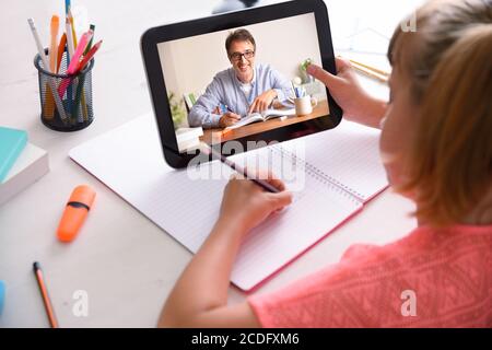 Online-Schüler mit Fernlehrer, die Klassen über das Tablet zu Hause. Erhöhte Rückansicht. Stockfoto