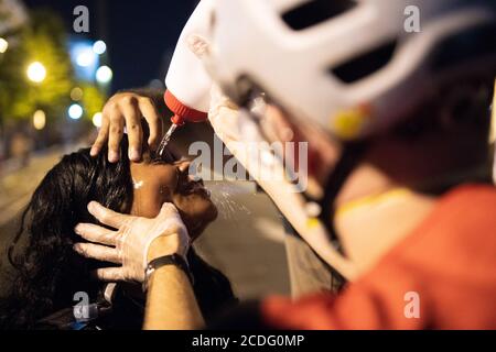 Washington, DC, USA. August 2020. Eine Protestierenden bekommt Pfefferspray aus den Augen gespült, nachdem sie es gesprüht hat, während sie versucht, einen Protestierenden vor der Verhaftung zu schützen, am Tag, an dem Donald Trump die republikanische Nominierung für den Präsidenten der Vereinigten Staaten am 27. August 2020 in Washington, DC offiziell akzeptiert. Quelle: Chris Tuite/Image Space/Media Punch/Alamy Live News Stockfoto