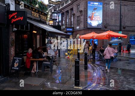 In einer regnerischen Nacht in Soho überqueren Londoners eine Fußgängerzone in der Old Compton Street, zu einer Zeit, in der kürzlich wiedereröffnete Bars und Restaurants während der Coronavirus-Pandemie am 27. August 2020 in London, England, verzweifelt nach Kundengeschäft sind. (Foto von Richard Baker / in Bildern über Getty Images) Stockfoto