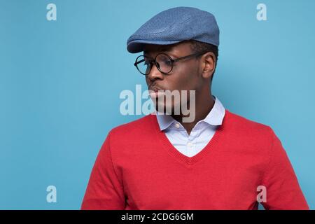 Hübscher afrikanischer junger Mann in blauer cao und Brille denken, beiseite zu schauen. Stockfoto