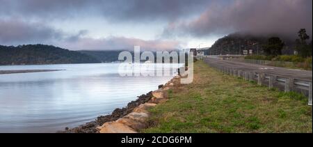 Ein nebliger Start in den Tag mit Wolken über dem Fluss, Straße und Inseln in Mooney Mooney am Hawkesbury River, Central Coast, NSW, Australien Stockfoto