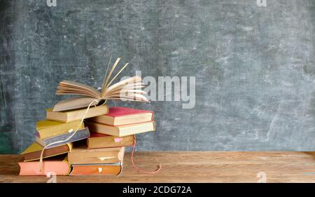 Stapel Bücher vor einer Tafel. Zurück zur Schule, Lesen, Bildung, Bibliothekskonzept Stockfoto