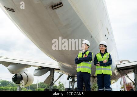 Asian Mann und Frau Ingenieur Wartung Flugzeug Arm gekreuzt und hält Schraubenschlüssel vor Flugzeug von Reparaturen, Fixes, Modernisierung und Renovierung i Stockfoto