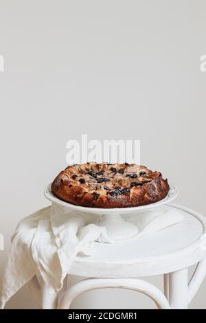 Hausgemachten Apfelkuchen mit Heidelbeeren auf einem Weißer Hocker mit einem Kopierplatz Stockfoto