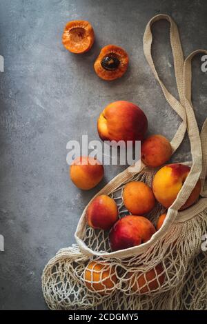 Flatlay mit frisch reifen Aprikosen im Marktsack auf Ein dunkler Hintergrund Stockfoto