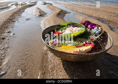 Ein Canang Sari gefüllt mit frischen Blumen in verschiedenen Farben. Es ist eine Form aufrichtiger Opfer der Hindu-Gemeinschaft in Bali. Direkt am Strand san Stockfoto