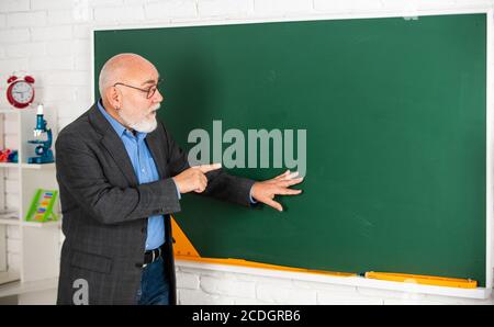 Beobachten und lernen. Bildung in der modernen Schule. Bärtiger Mann zeigen etwas. Kopie spce. Senior Lehrer erklären Thema an der Tafel. Lehrer der Geographie. Klassenzimmer mit Karte. Zurück zur Schule. Stockfoto