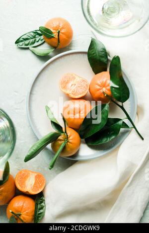 Mandarinen mit Blättern auf blauem Hintergrund mit Getränk Stockfoto