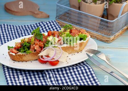 Ein großes Sandwich mit Avocado, Tomate, Basilikum und Käseaufstrich. Toast auf weißem Baguette Brot. Nahaufnahme Stillleben auf dem Tisch. Sandwich-Snacks Stockfoto