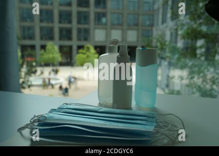 Verschiedene Händedesinfektionsmittel mit mehreren Gesichtsmasken im Büro als neue Norm für Mitarbeiter, um Hygienevorschriften und soziale Distanzierung zur Prävention einzuhalten. Stockfoto