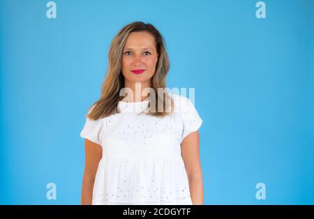 Frau im weißen Hemd lächelnd auf blauem Hintergrund Stockfoto