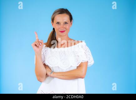 Frau in weißem Hemd zeigt auf blauem Hintergrund Stockfoto