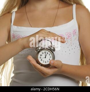 Das Mädchen hält einen Wecker in den Händen Stockfoto