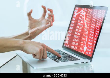 Gestresste Handbewegung des Investors, der Geld in den Börsencrash verliert, während er auf einem Laptop-Computer tippt. Die rote Karte für die Wirtschaft fällt. Nahaufnahme. Stockfoto