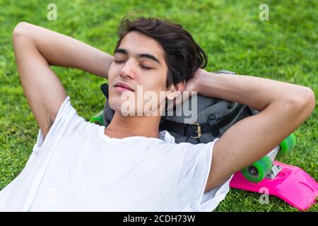 Nahaufnahme eines entspannten jungen Mannes, der im Sommer auf dem Rasen in einem Outdoor-Park schläft. Stockfoto