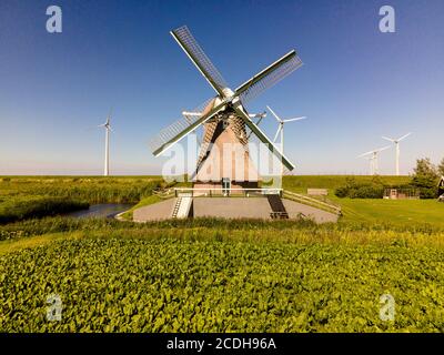 Alte Windmühle in Kombination mit neuen Windturbinen, die saubere Energie erzeugen Stockfoto