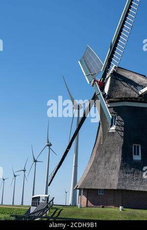 Alte Windmühle in Kombination mit neuen Windturbinen, die saubere Energie erzeugen Stockfoto