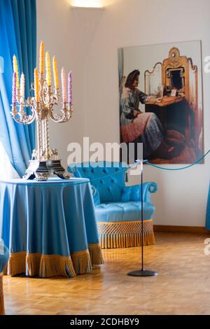 Gala Dalí Castle House-Museum EINE Ecke im Schlafzimmer von Gala. Blaue Vorhänge, goldene Fransen, farbige Kerzen im Kerzenständer mit vielen Armen. Stockfoto